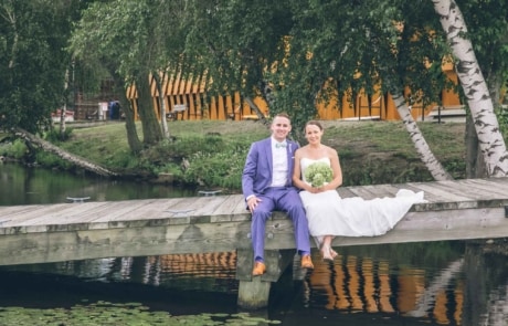 newlyweds sitting on a wooden dock by a lake, photographed by Eivan's in Boston