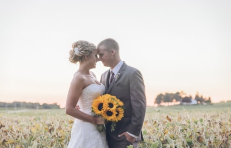 man in black suit and woman in white wedding dress holding bouquet of flowers