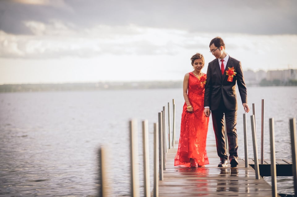 man in black suit and woman in red dress standing on sea dock during daytime