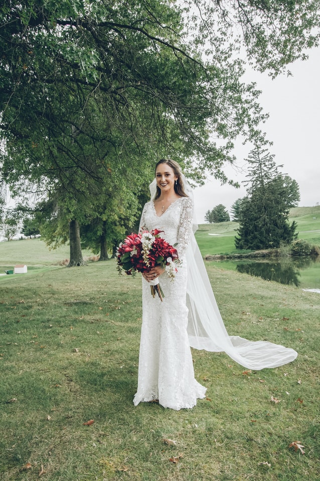 woman in white long sleeve dress holding bouquet of flowers