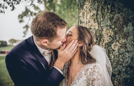 man and woman kissing near tree during daytime