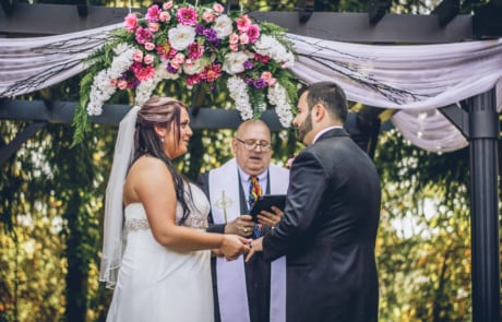 man in black suit holding bouquet of flowers beside woman in white sleeveless dress