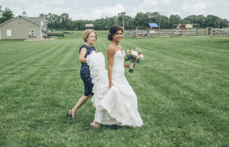 woman in white tube dress holding bouquet of flowers standing on green grass field during daytime