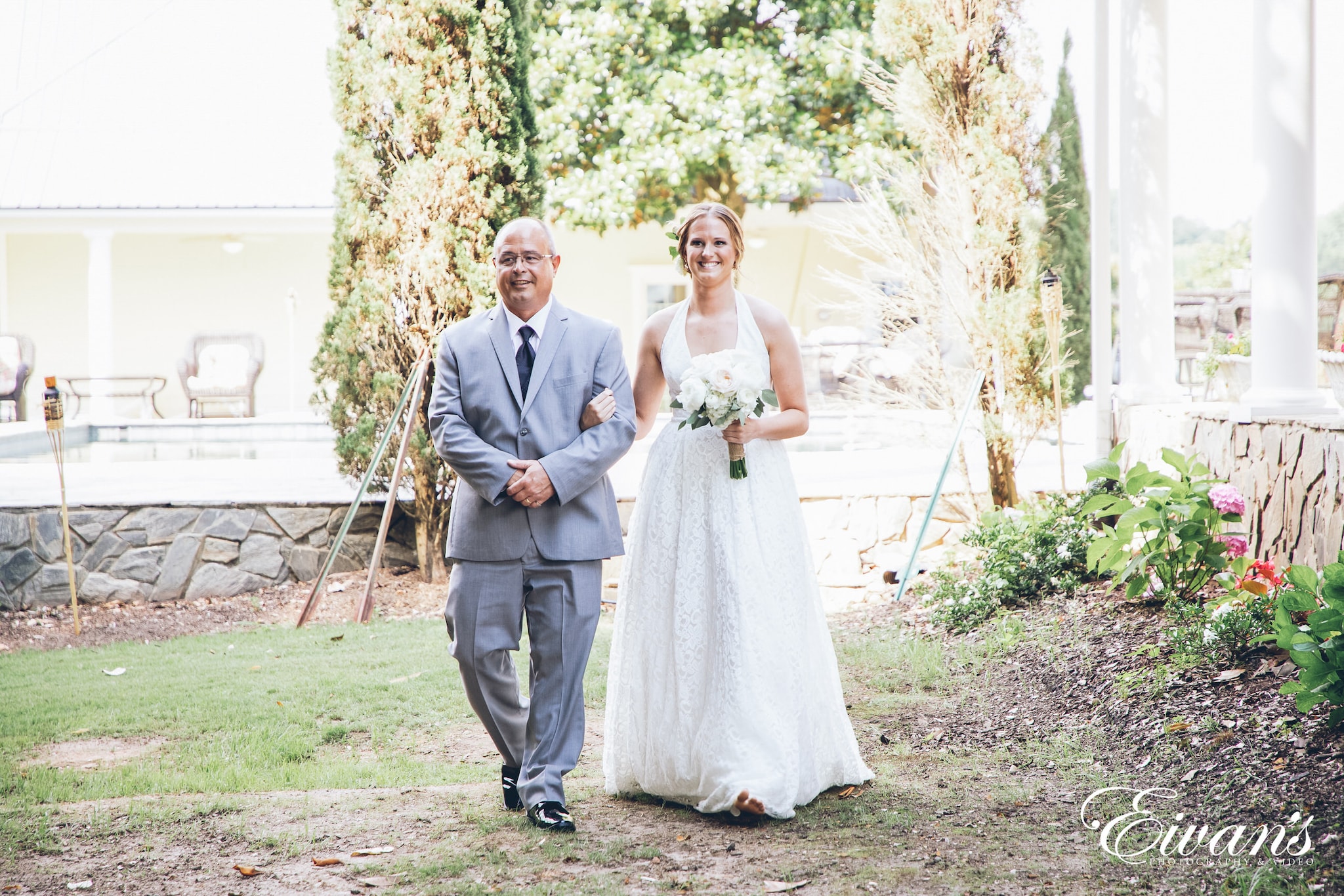 woman in a white dress walking down the aisle with her father