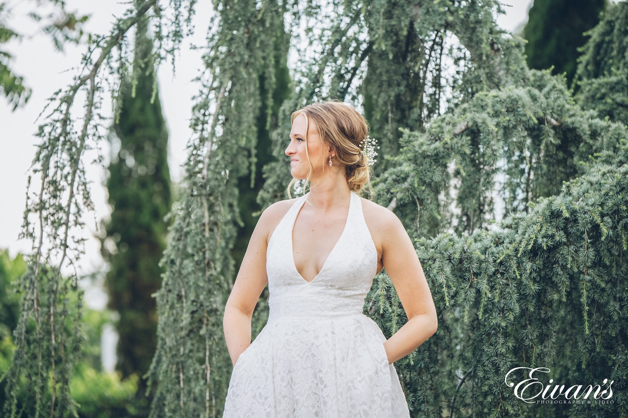 bride wearing a white dress posed in front of trees