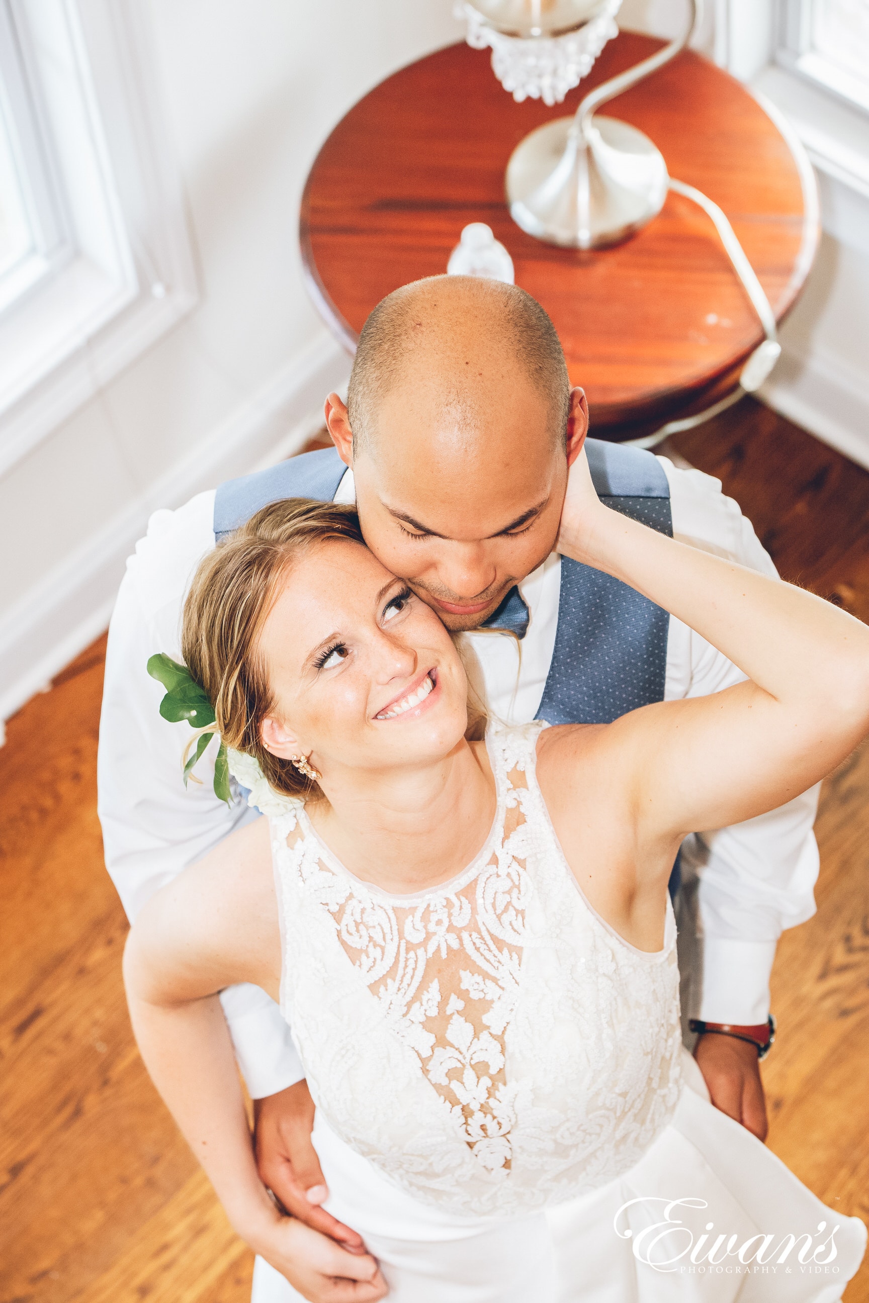 man hugging woman in a white dress from behind indoors