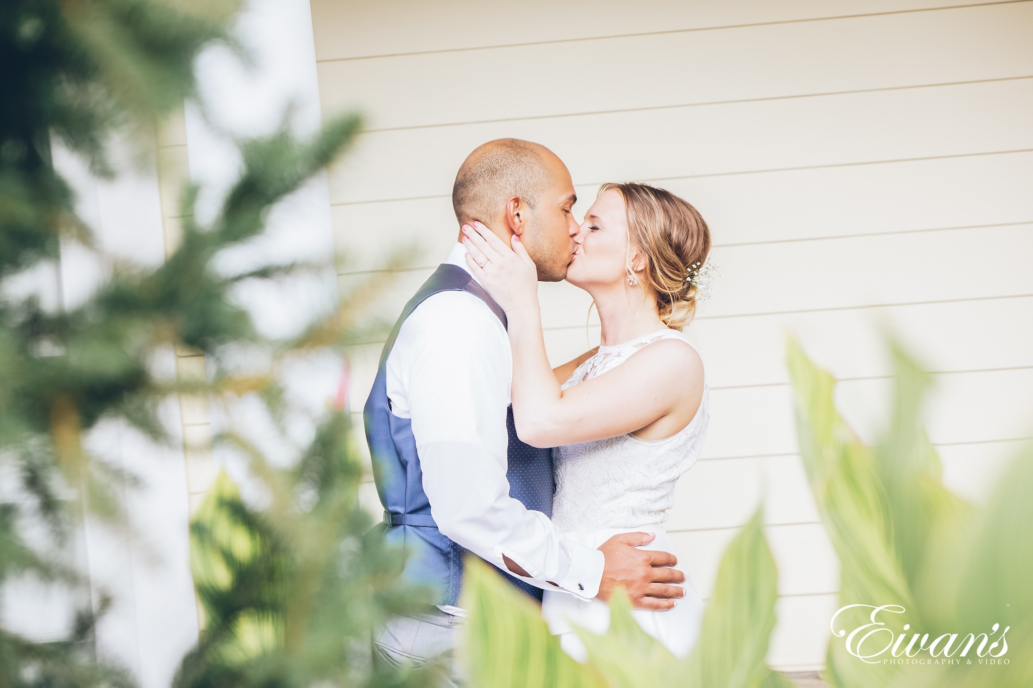 man wearing a white shirt and woman wearing a white dress kissing