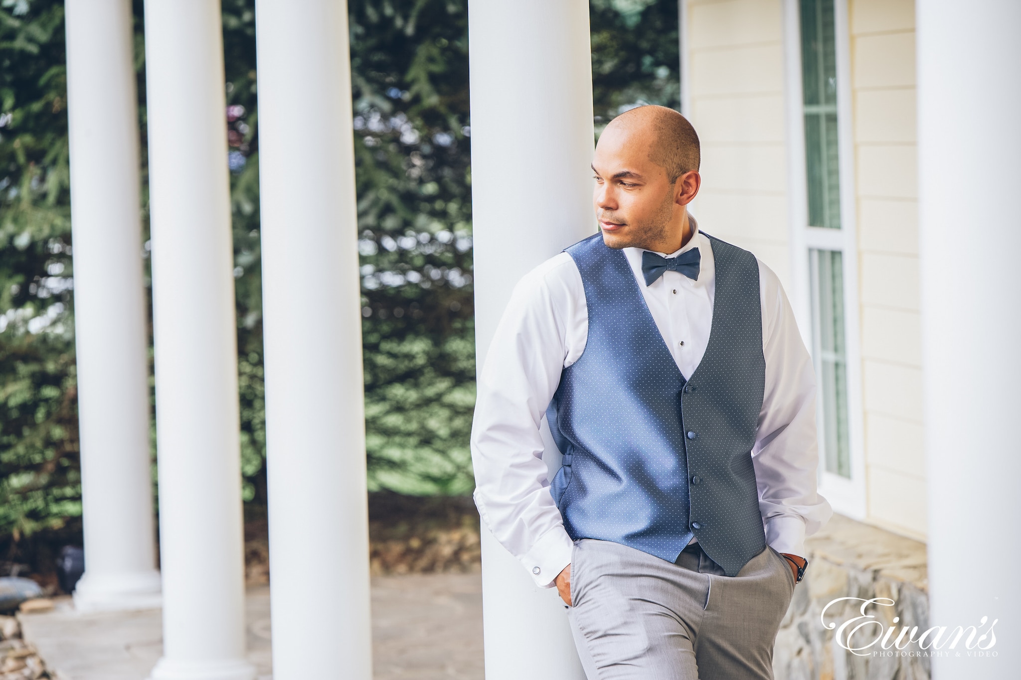 man in a blue suit posed against white pole