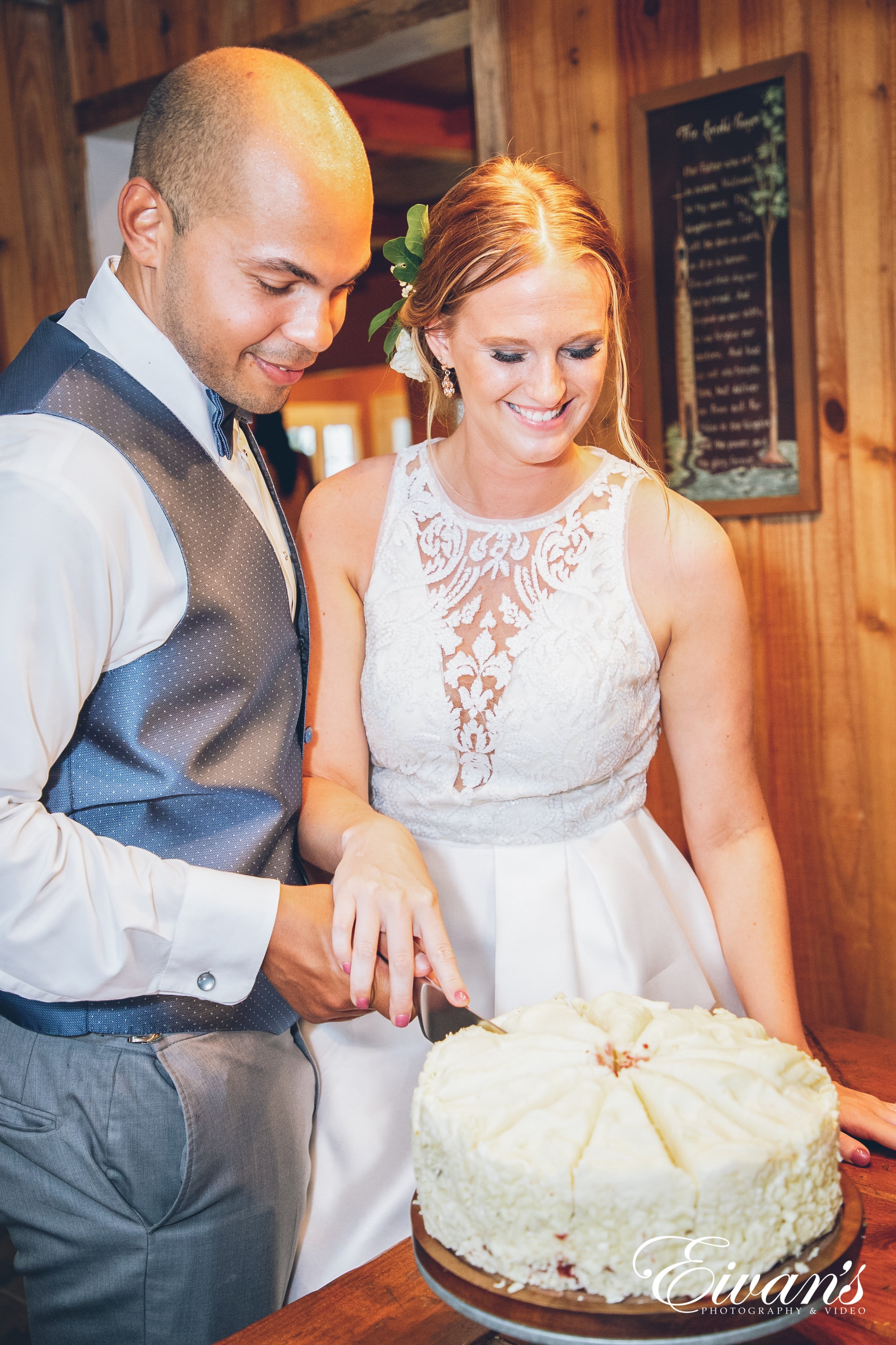 man and woman in a white dress cutting a cake