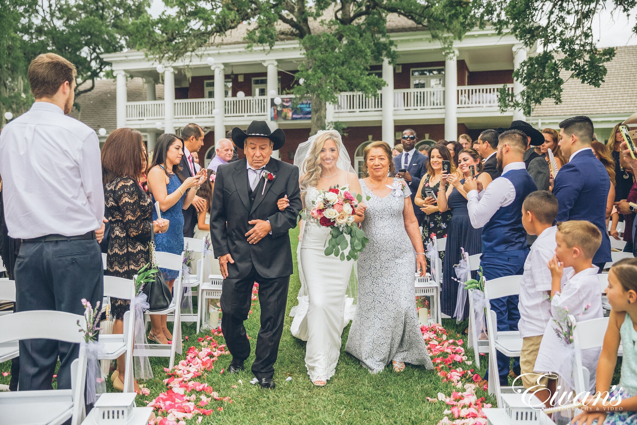 woman in white wedding gown standing between man in black suit and woman in white wedding