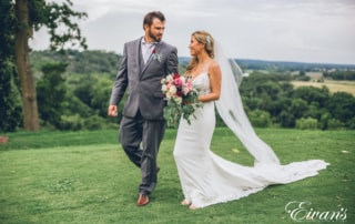 man in black suit and woman in white wedding dress holding bouquet of flowers