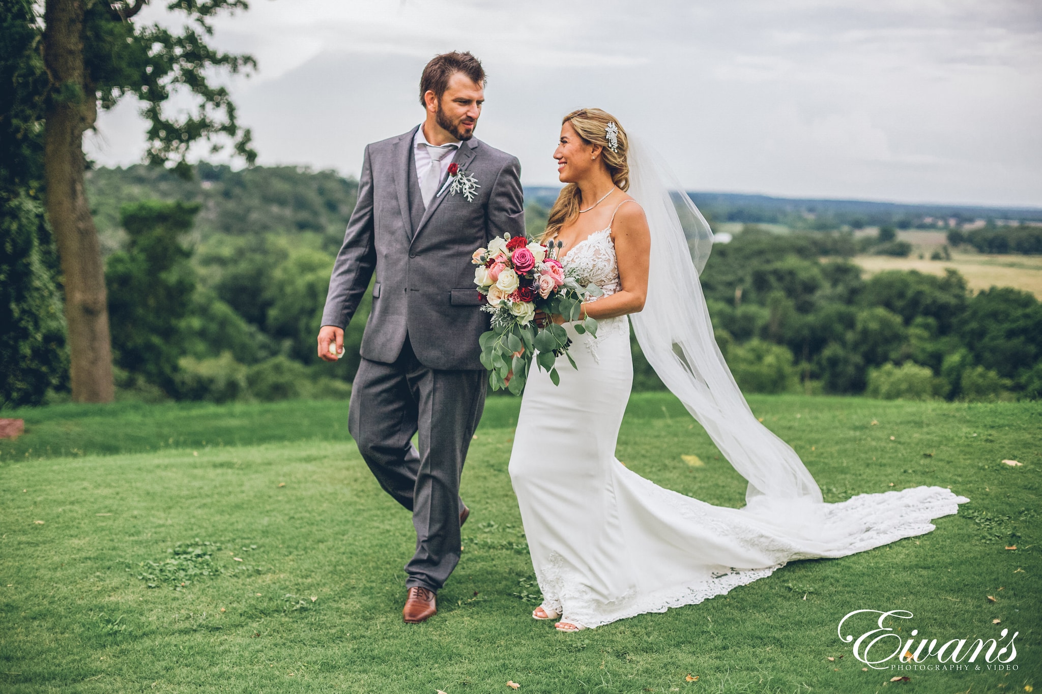 man in black suit and woman in white wedding dress holding bouquet of flowers