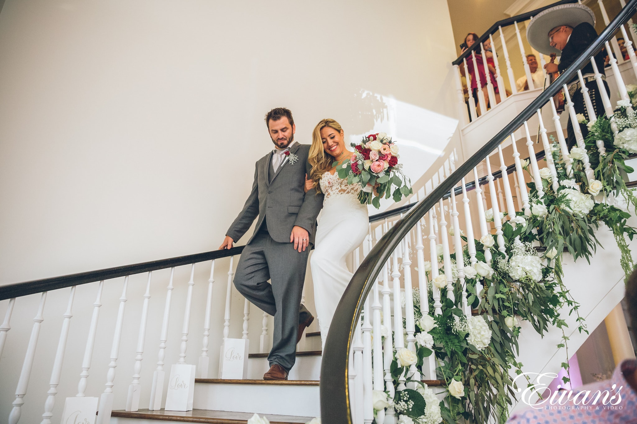 man in gray suit and woman in white wedding dress standing on staircase