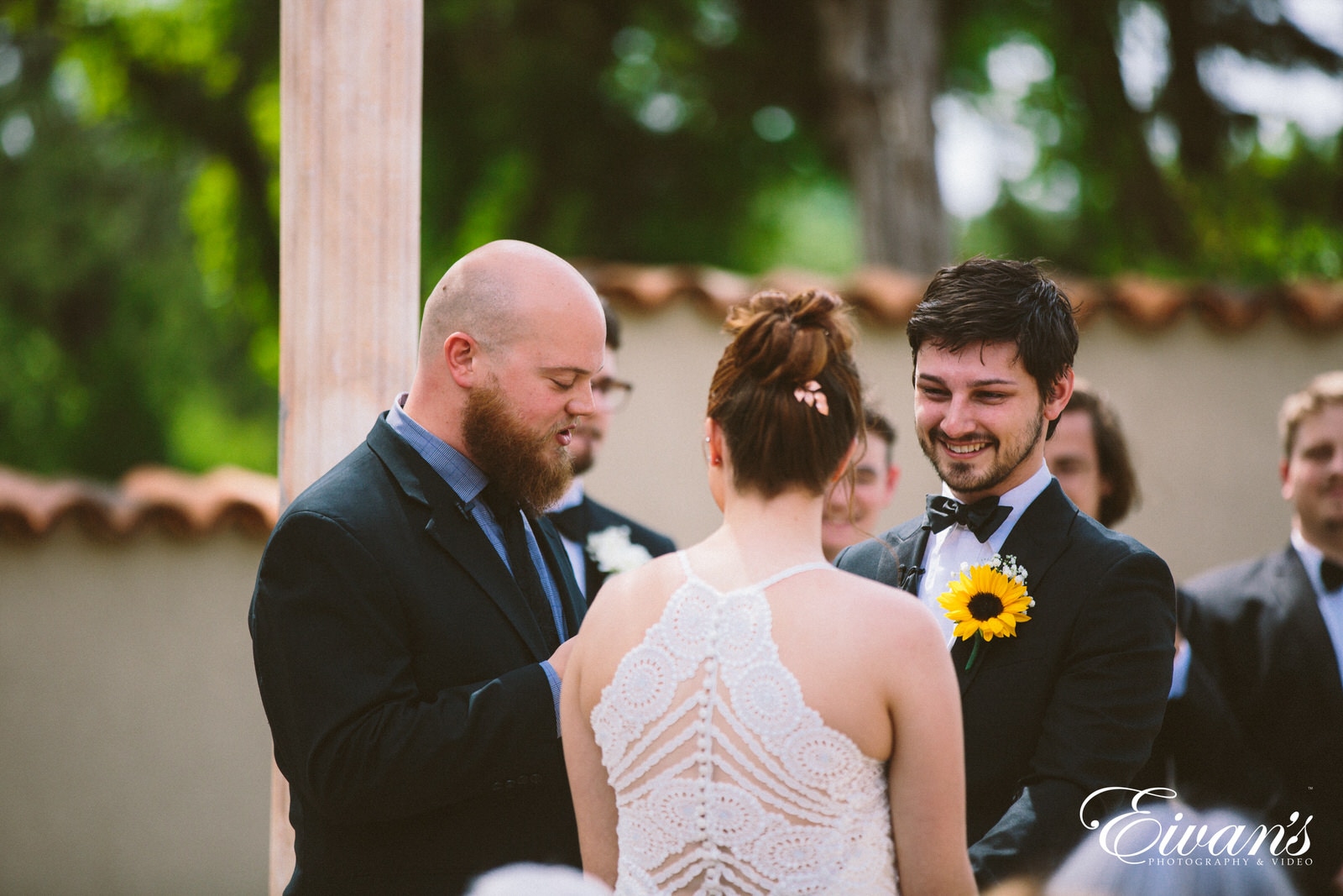 man in black suit jacket and woman in white floral lace wedding dress