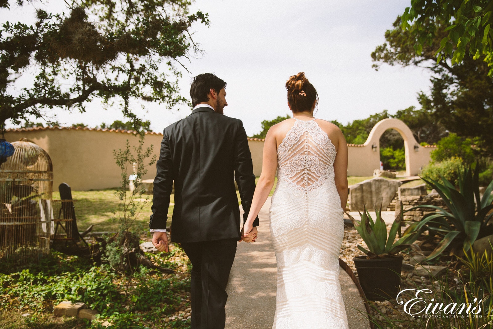 man in black suit and woman in white wedding dress walking on green grass field during