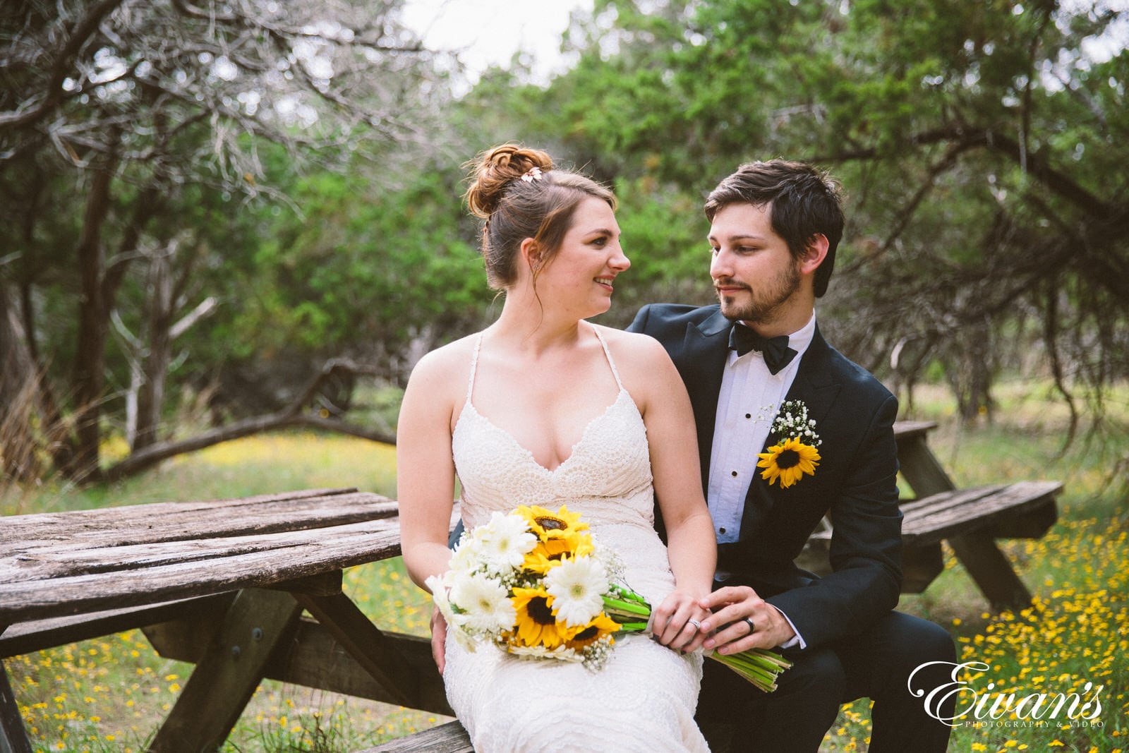 woman in white wedding dress sitting on brown wooden bench