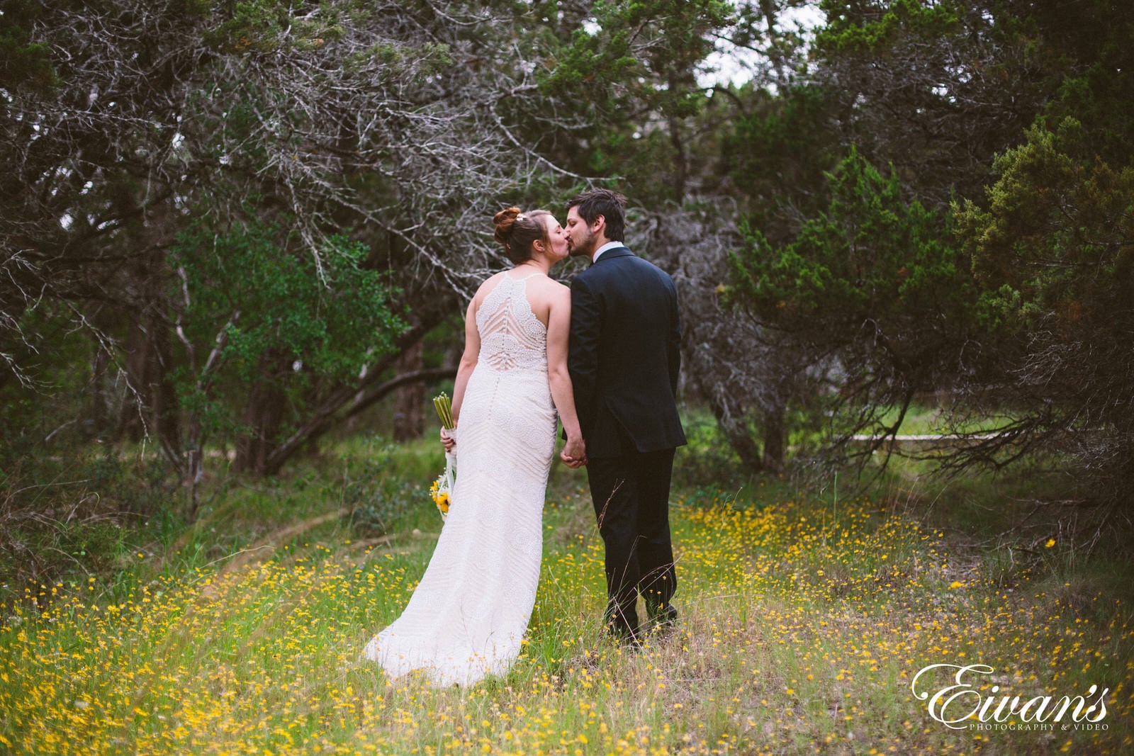 man and woman in wedding dress walking on green grass field surrounded by trees during daytime