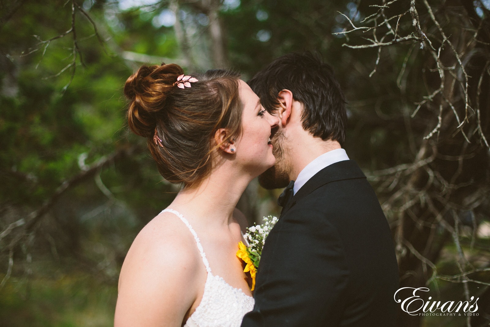 man in black suit kissing woman in white wedding dress