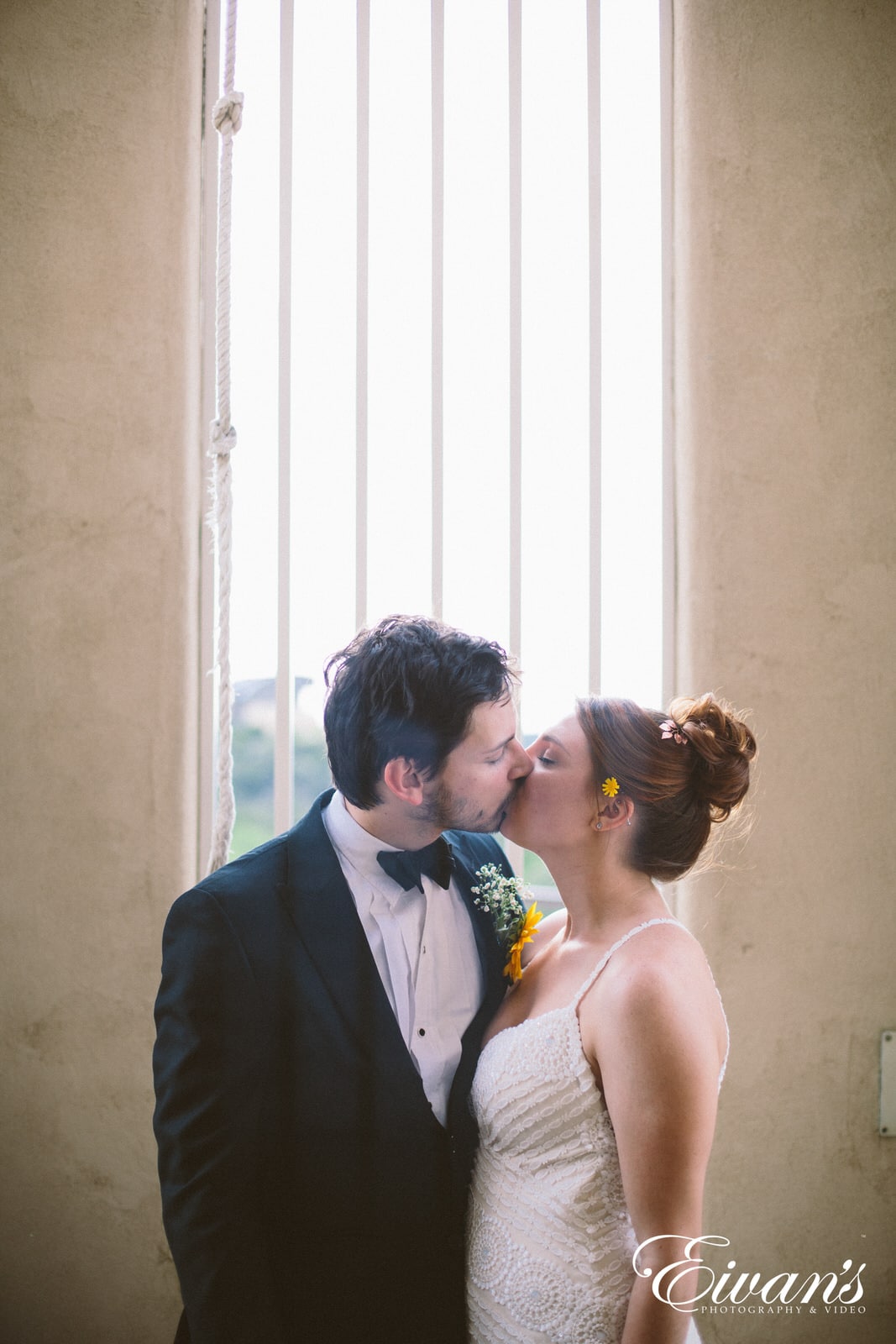 man in black suit kissing woman in white sleeveless dress