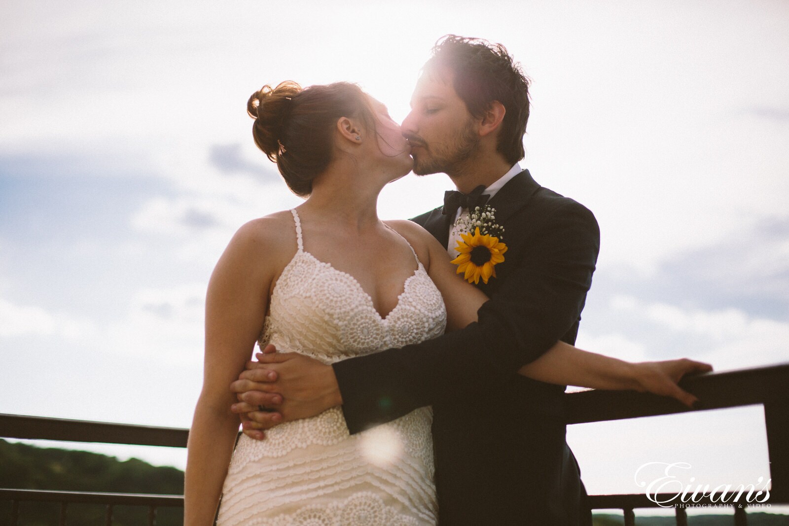 man in black suit kissing woman in white wedding dress