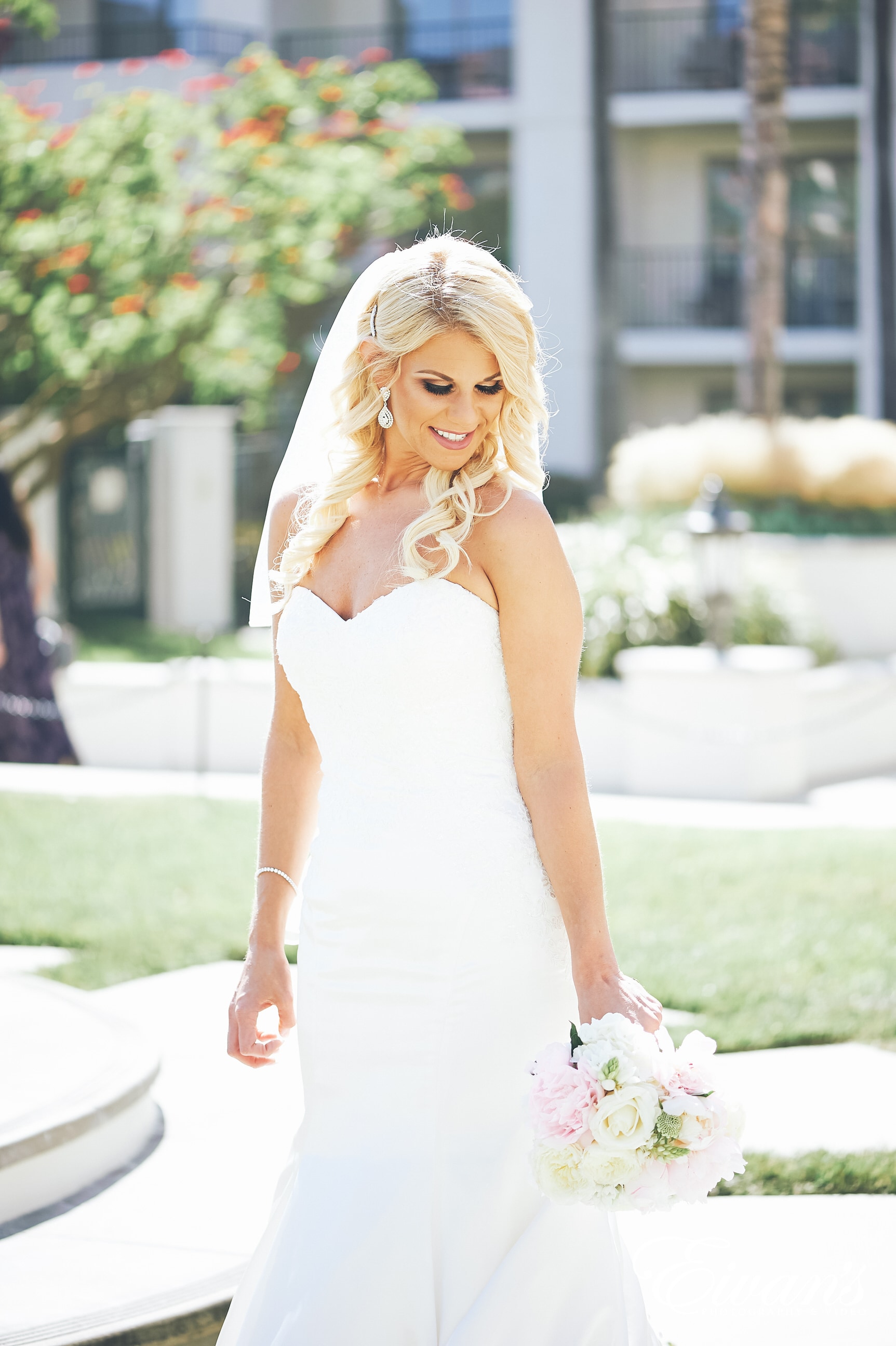 woman in white spaghetti strap dress holding bouquet of flowers