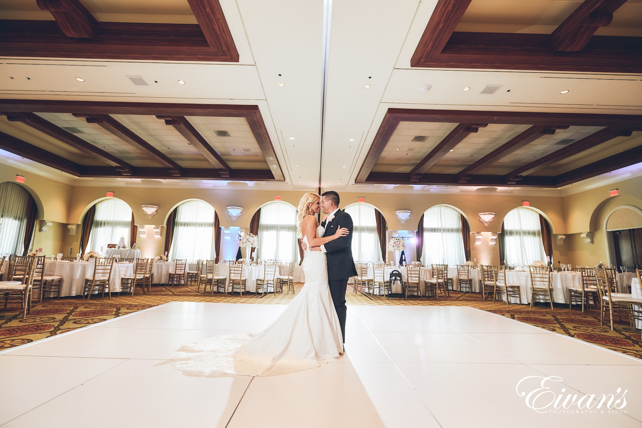 man and woman in a white dress hugging on a dance floor