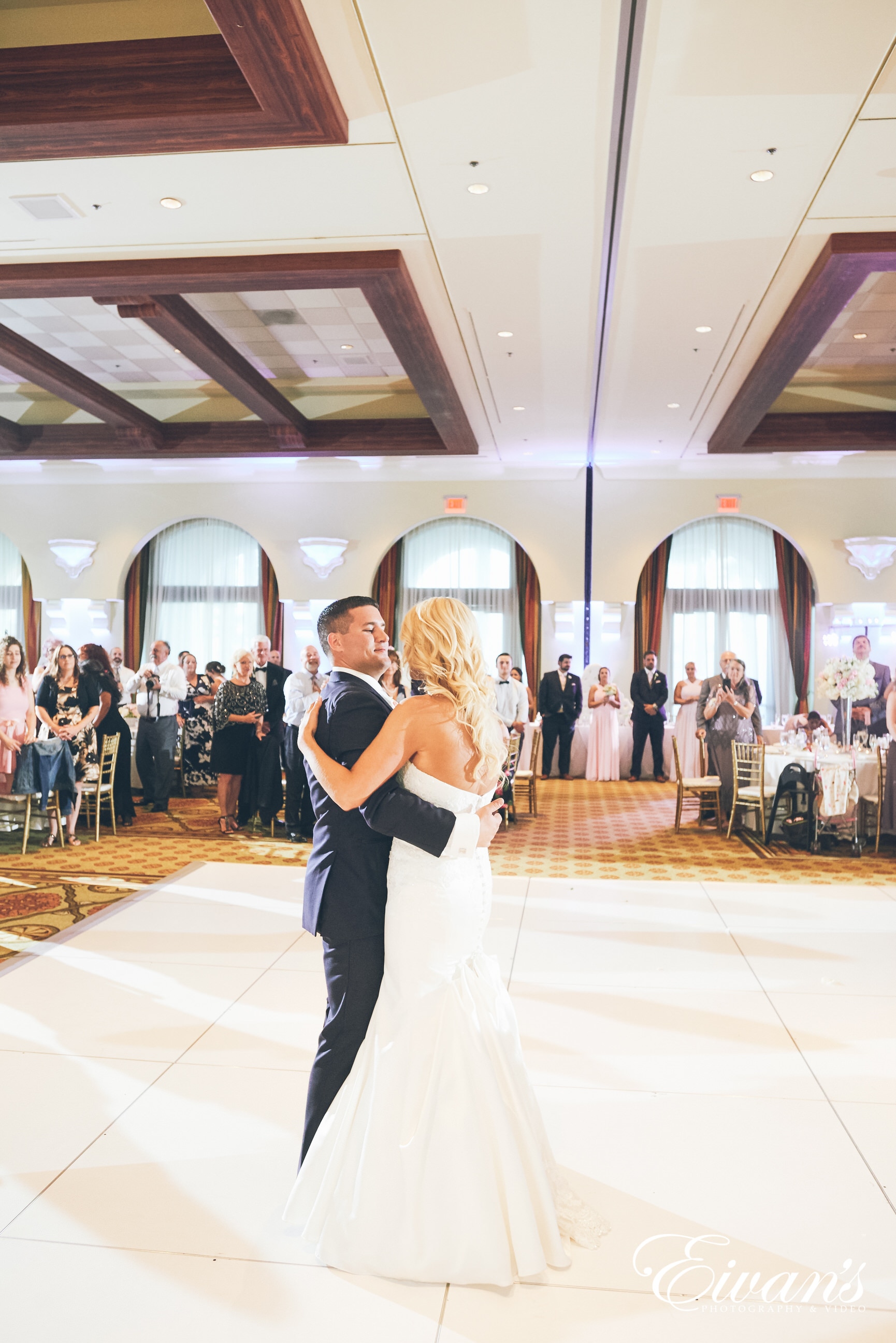 man and woman in a white dress hugging and dancing indoors