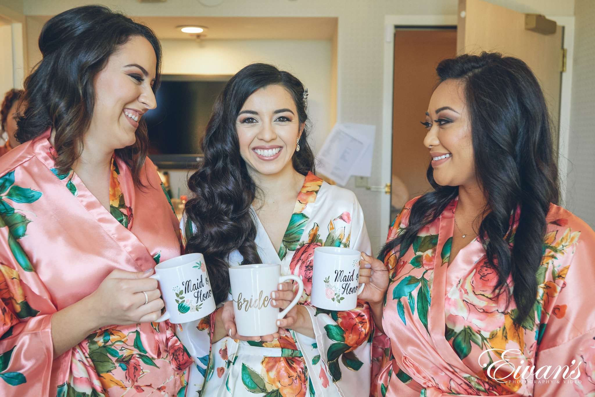 three women wearing floral robes holding mugs