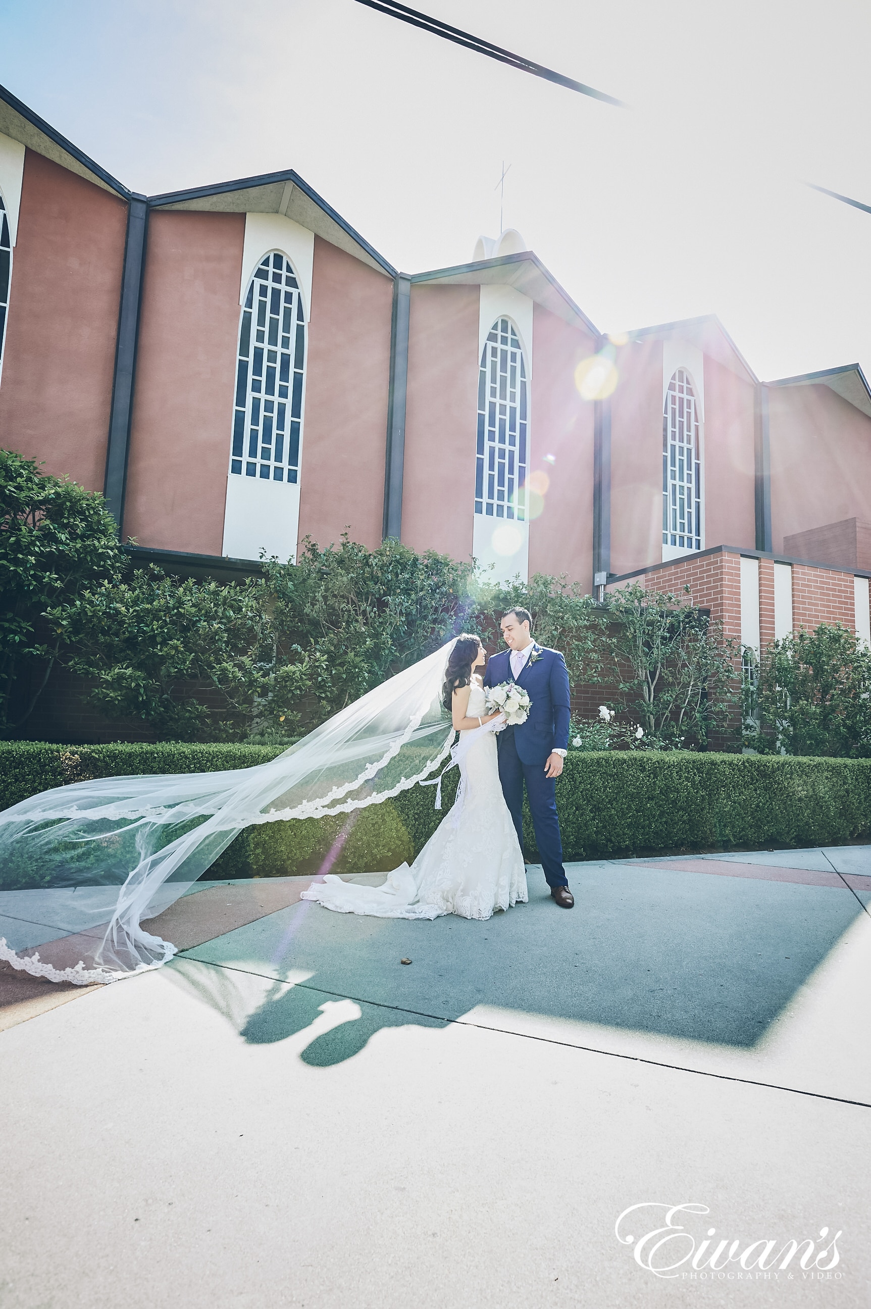 man and woman in a white dress posed outside a church