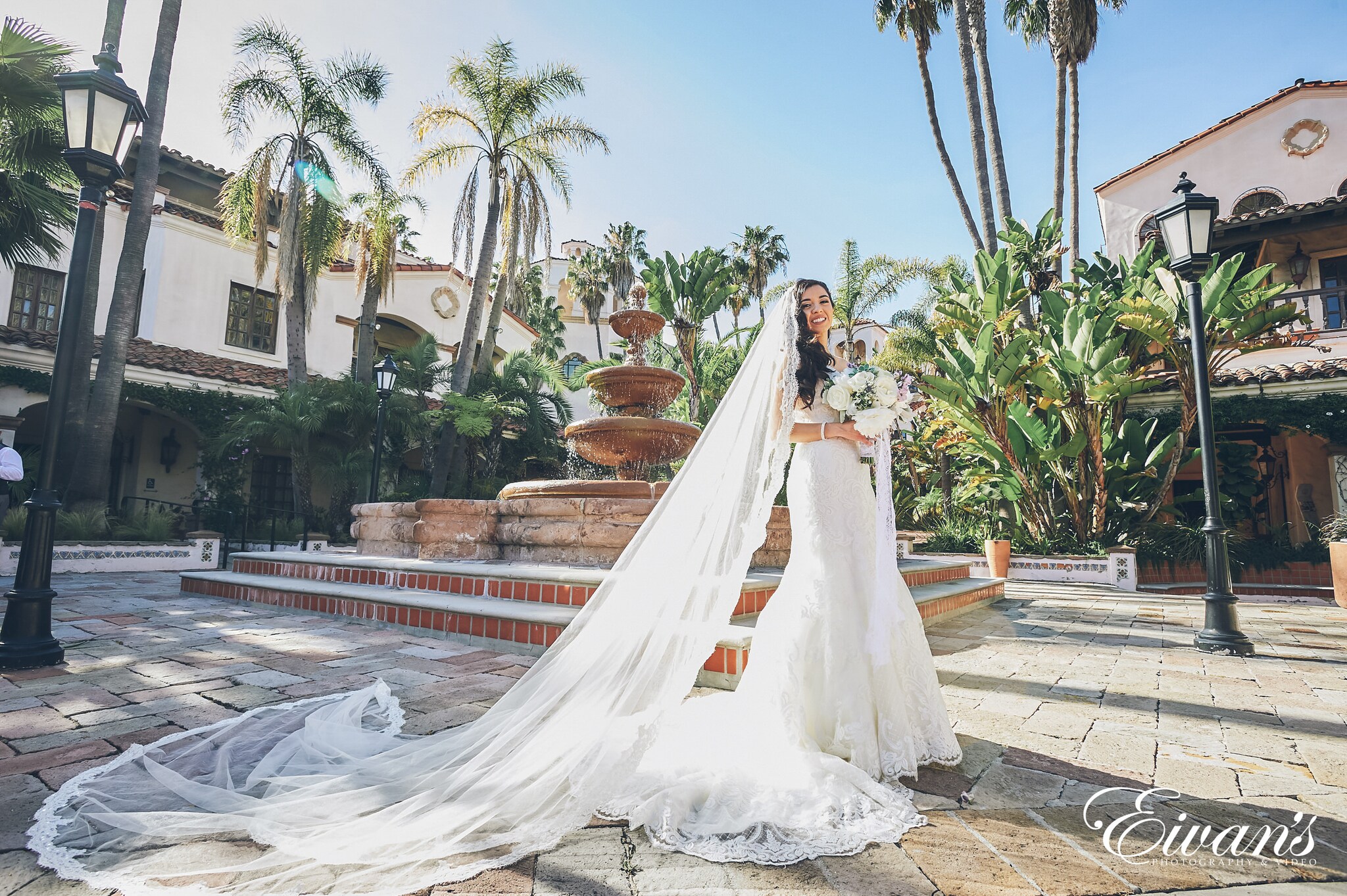 woman in a white dress and long viel posed in from of a fountain