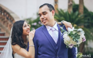 man in blue suit kissing woman in white wedding dress