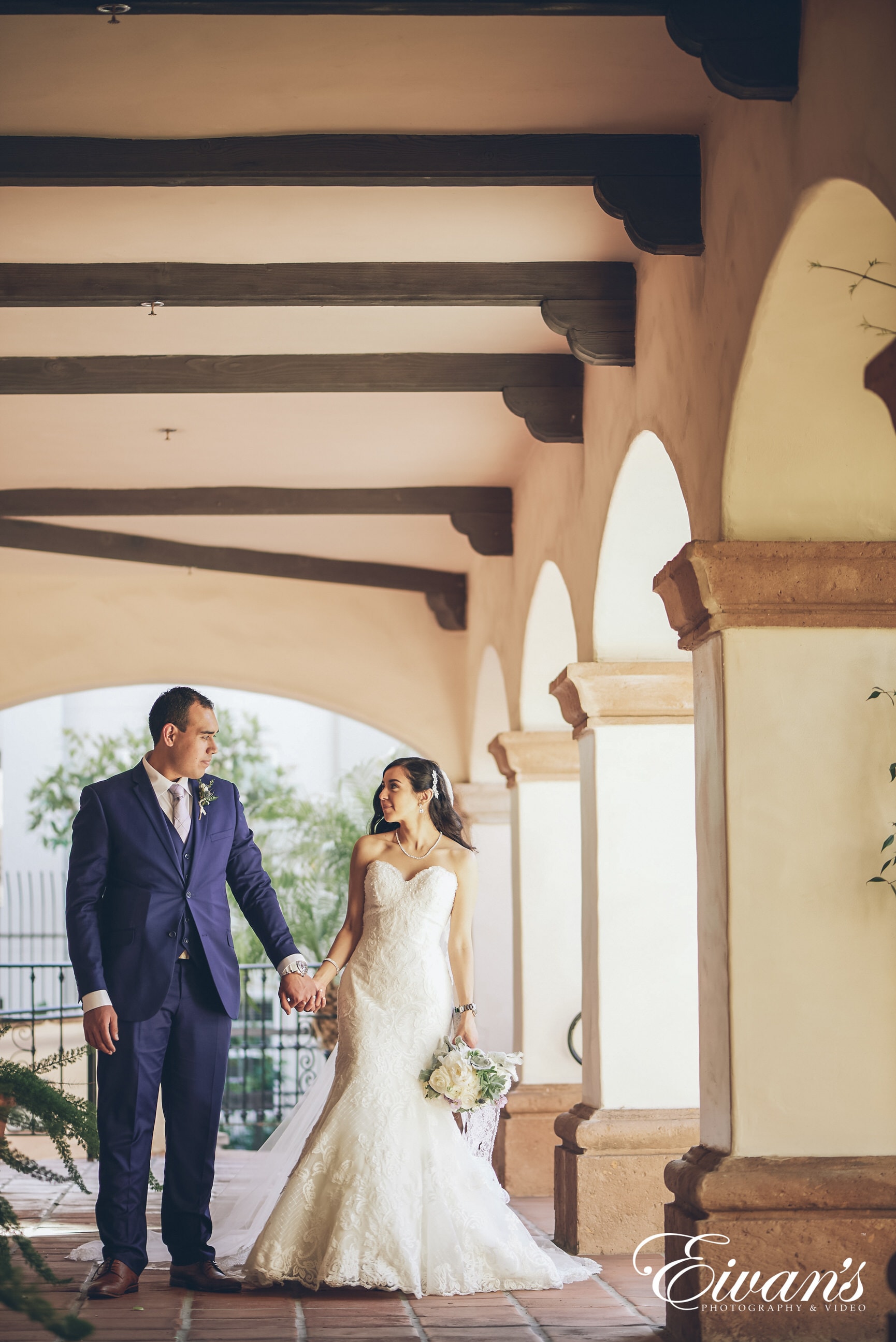 man in suit and woman in a white dress holding hands