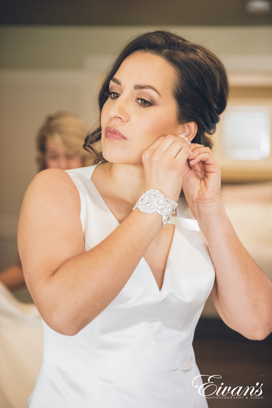 portrait of a woman wearing a white dress putting on earrings