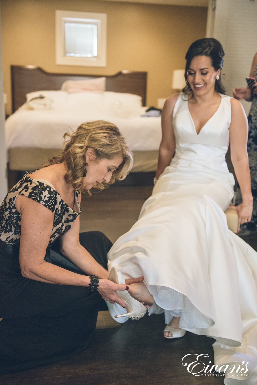 mother of the bride putting on brides shoes