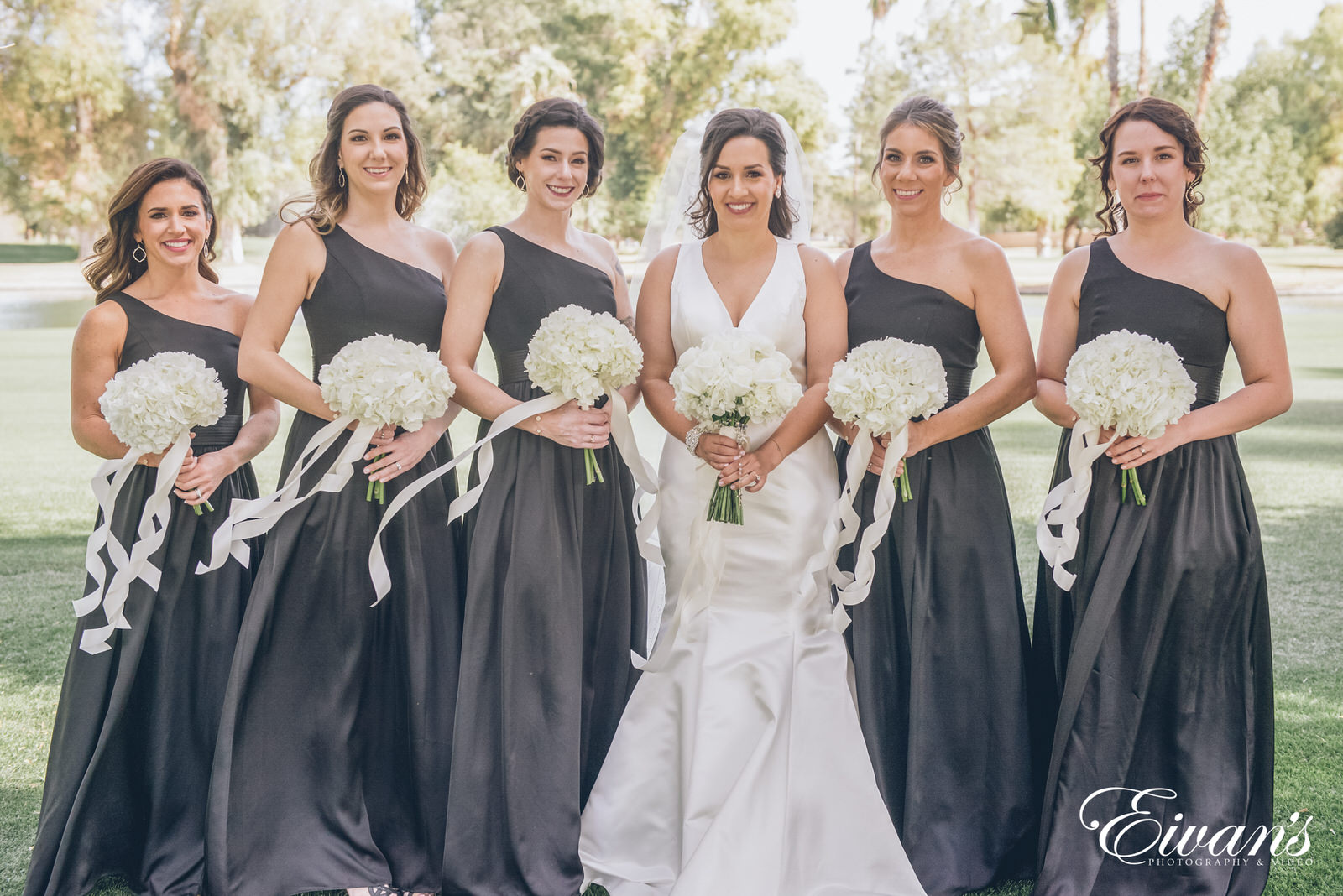 married woman standing next to bridesmaids wearing black dresses