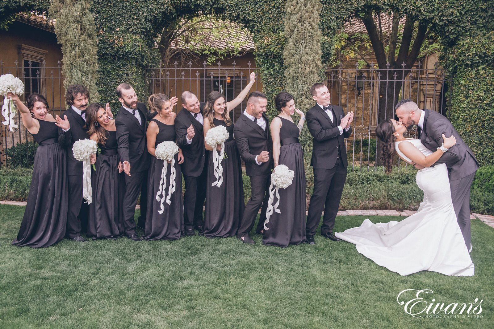 married man and woman kissing in front of a bridal party