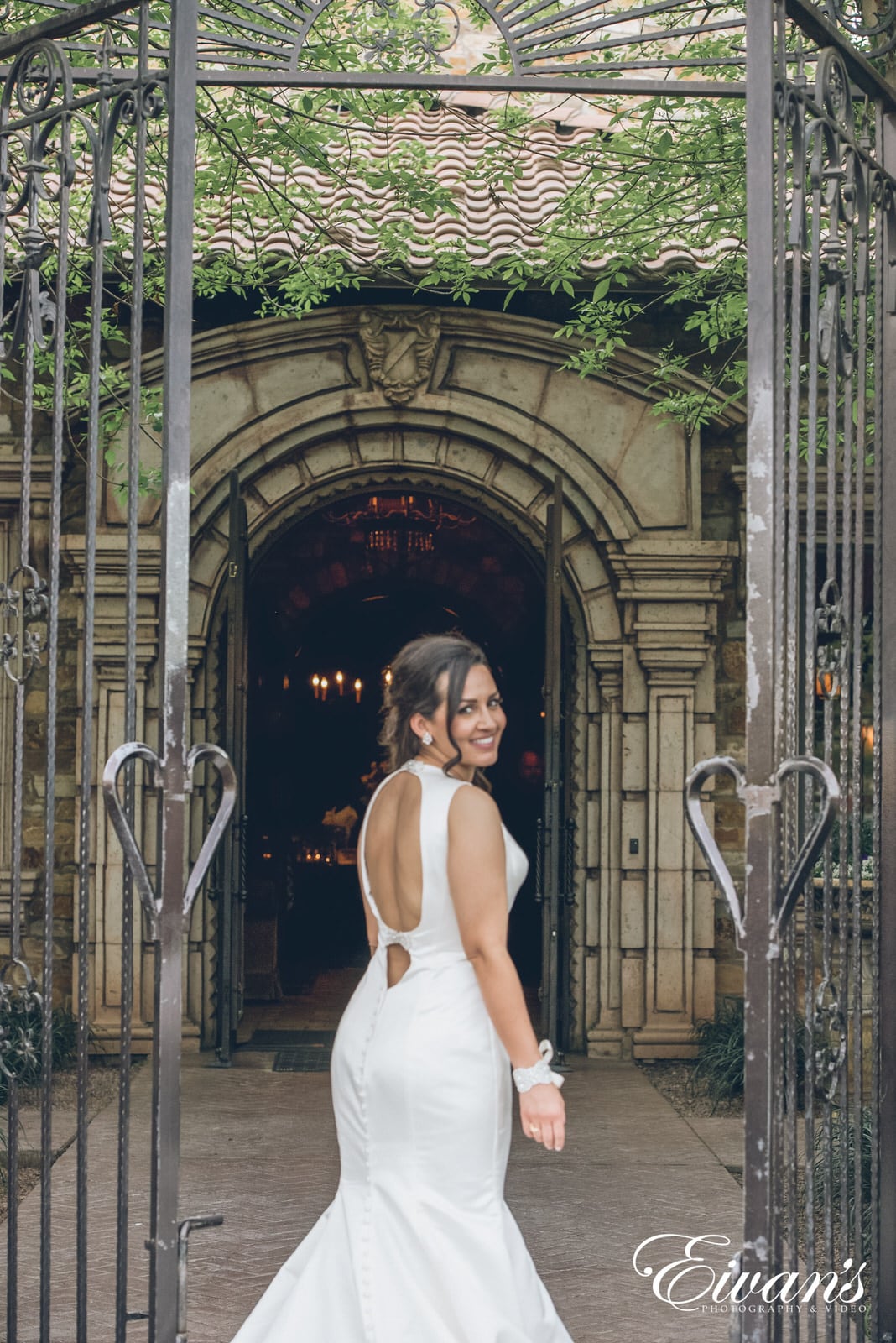 woman in a white dress standing in between open gates