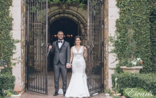 man in black suit and woman in white wedding dress standing in front of brown wooden