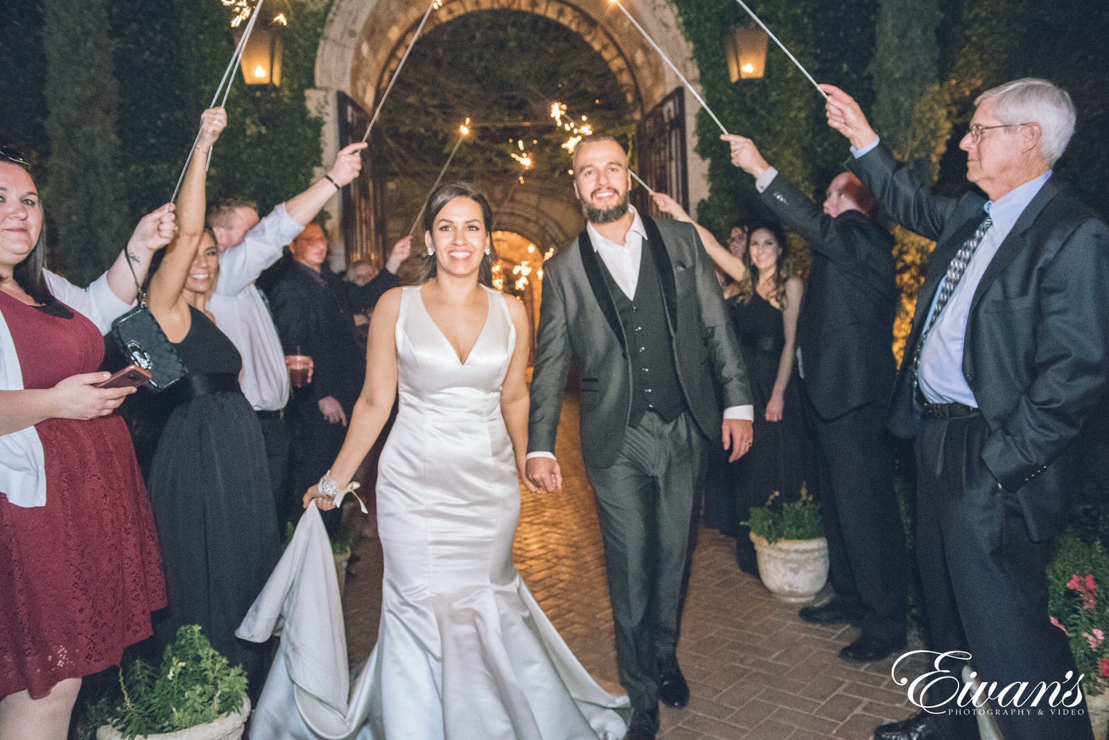 married man and woman walking through guests with sparklers