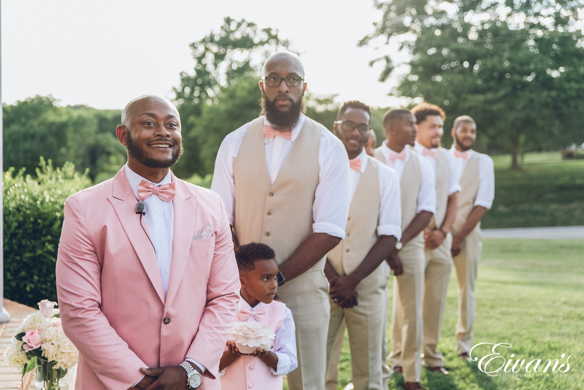 group of men in pink suit standing on green grass field during daytime