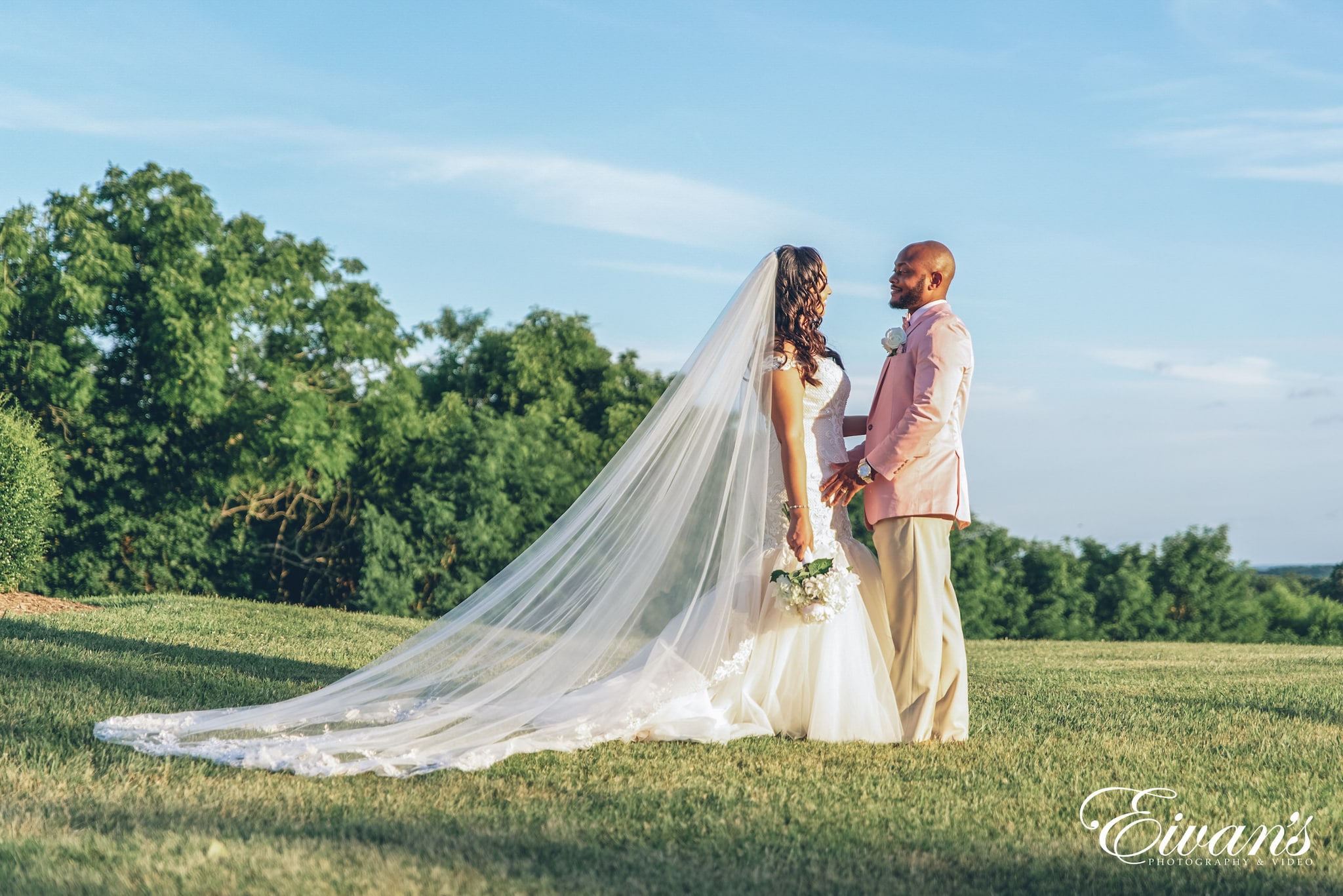 woman in white wedding gown standing on green grass field during daytime