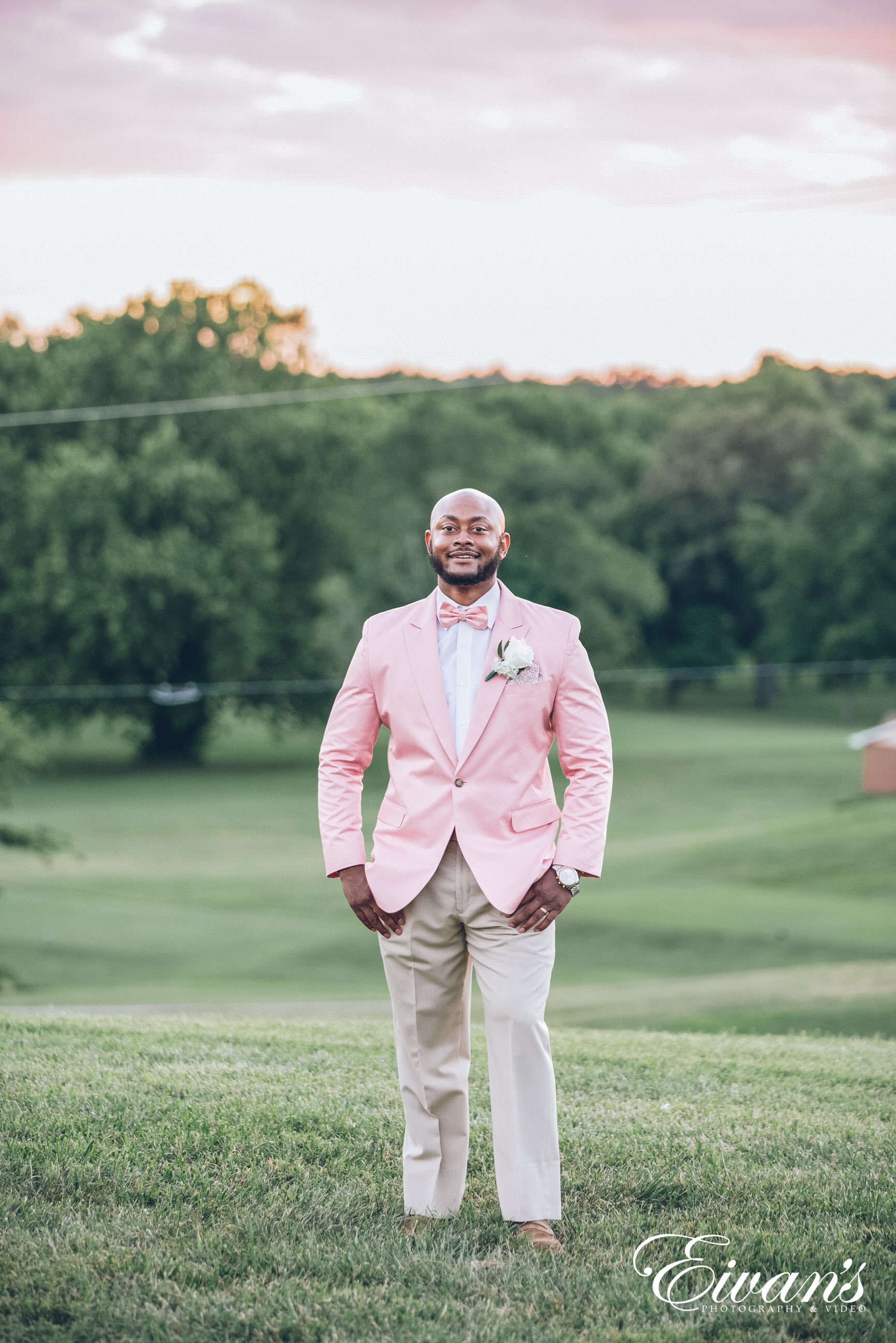 man in white dress shirt and white pants standing on green grass field during daytime