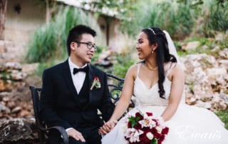 man in black suit jacket sitting beside woman in white wedding dress