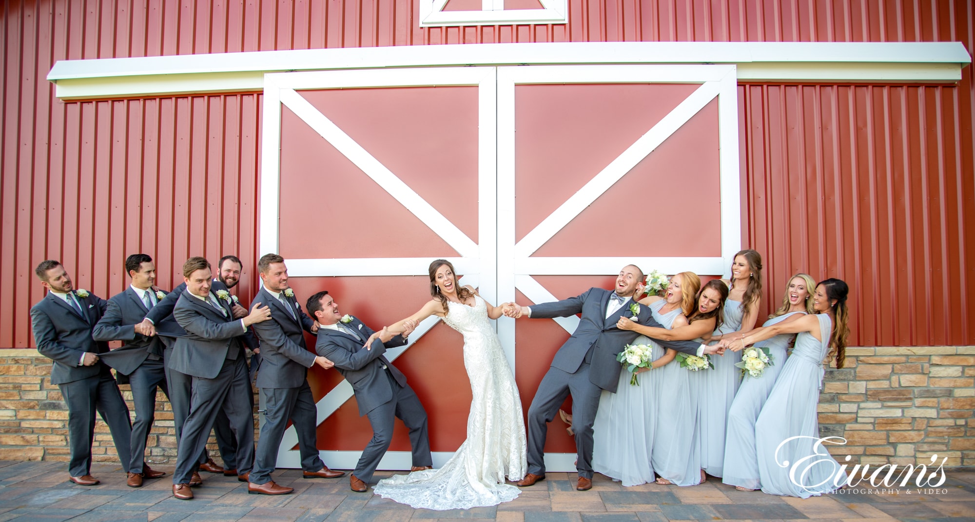 Bridal party posed in front of big red barn doors