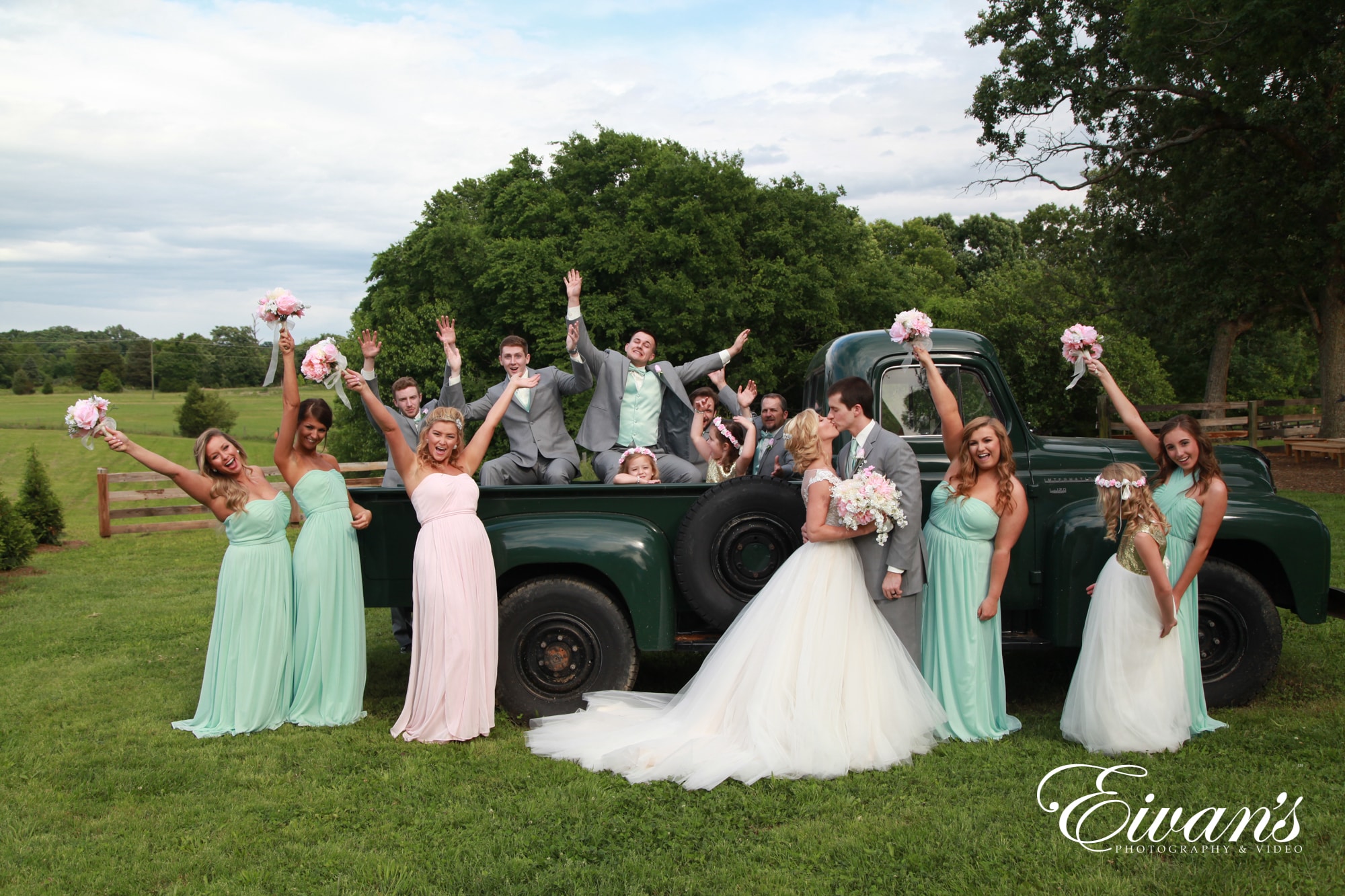 bridal party posed in front of a green pickup truck