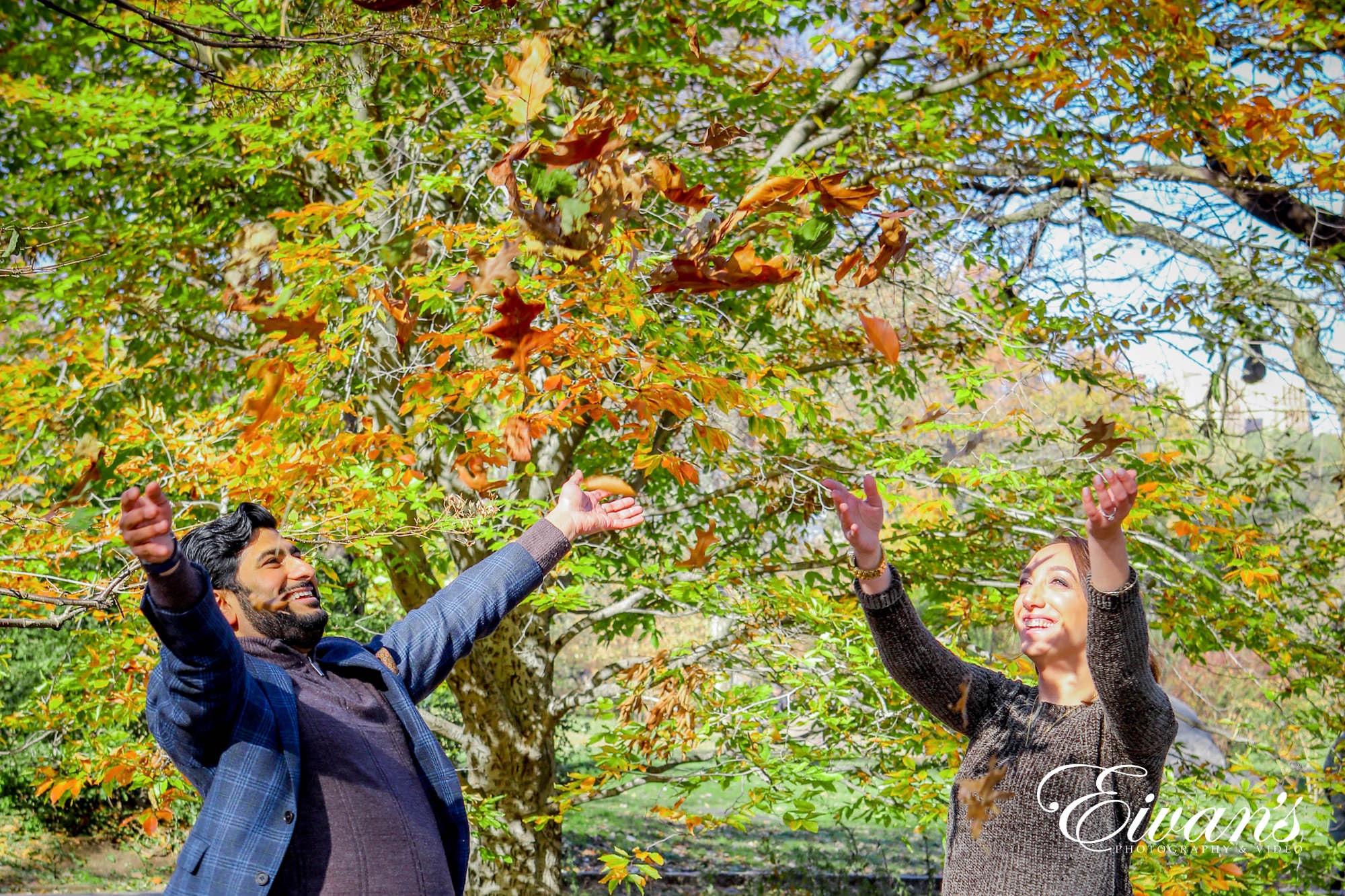 engaged couple throwing autumn leaves in the air