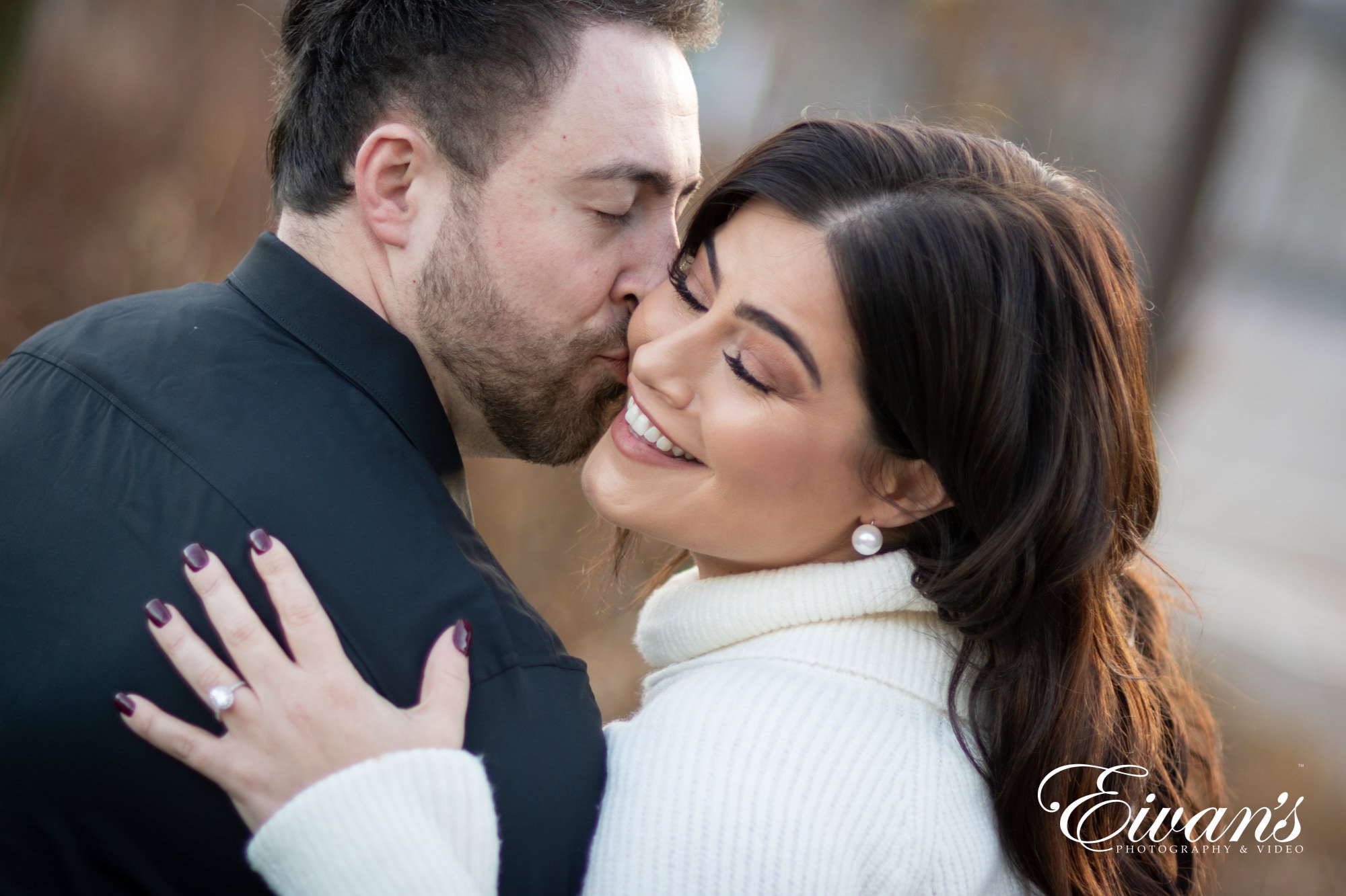 engaged man kissing his fiancee on the cheek