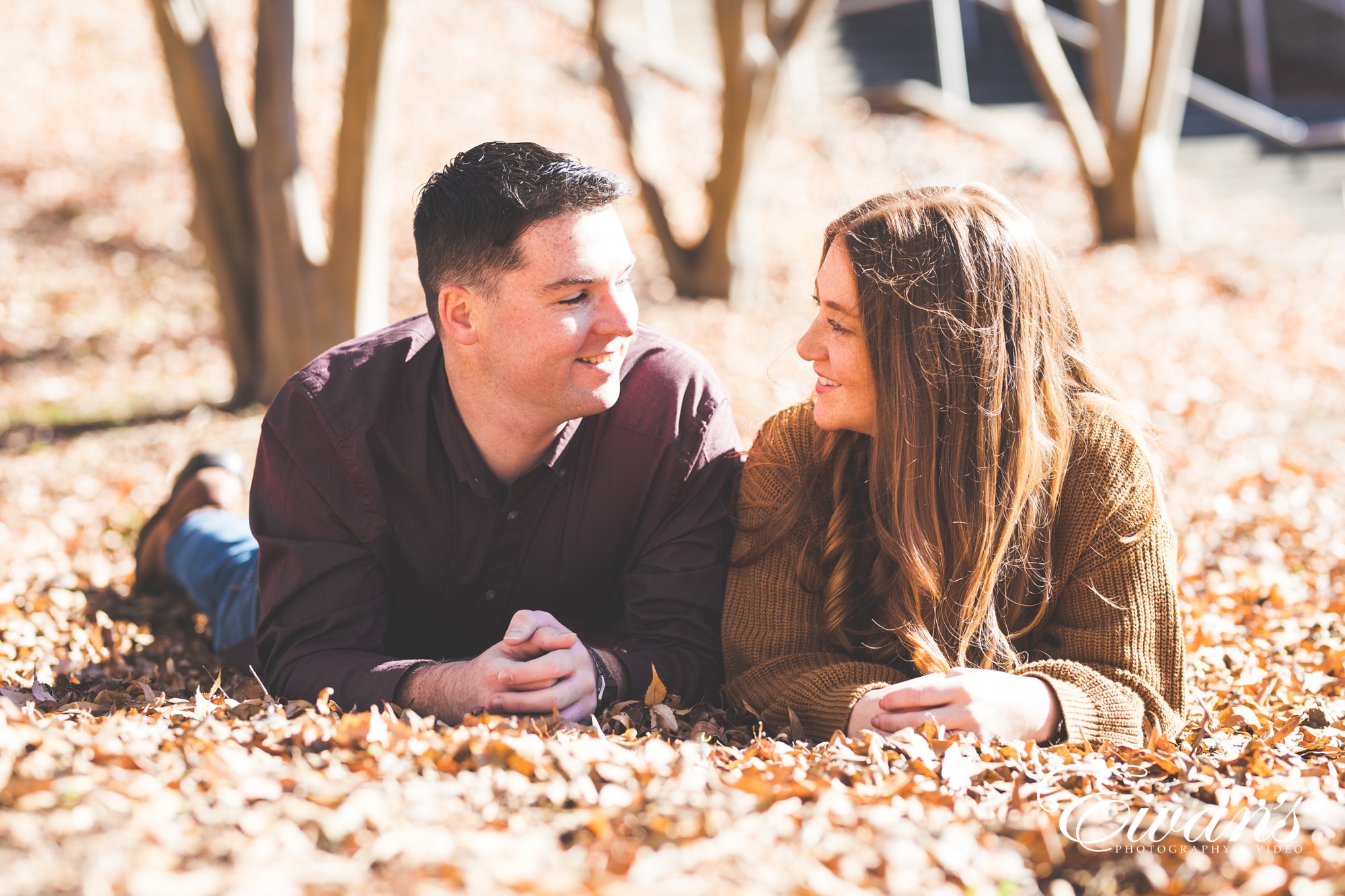 romantic-ideas-for-fall-engagement-photos engaged couple posed on the ground surrounded by autumn leaves