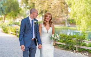 bride and groom walking beside each other in a park