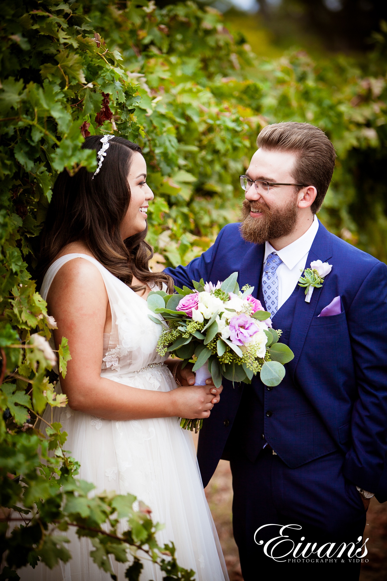 image of a bride and groom standing in front of a wall of greenery